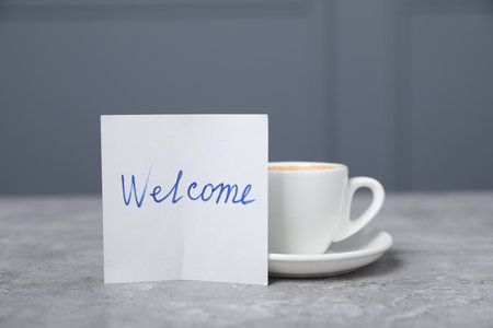 Sticky note with word Welcome and coffee on grey table, closeupの写真素材