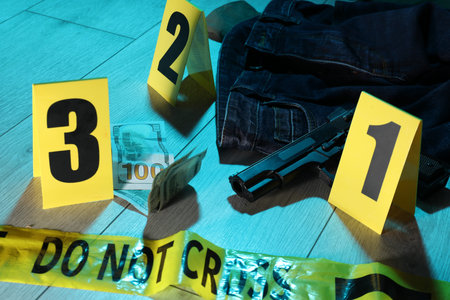 Forensic expertise. Crime scene with evidence, markers and police tape on floor, closeup. Color...
