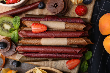 Tasty candied leather rolls, fruits and berries on wooden table, flat layの写真素材