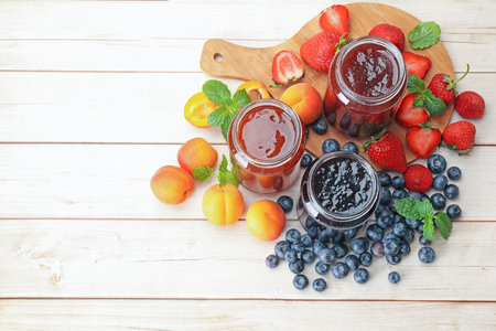 Different jams in jars and ingredients on white wooden table, flat lay. Space for textの写真素材