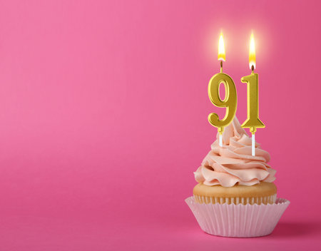 Yummy cupcake with burning number shaped candles on pink background, space for text. 91th birthday or other special occasionの写真素材