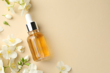 Essential oil and beautiful jasmine flowers on beige background, flat lay. Space for textの写真素材