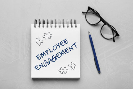 Employee engagement. Words and drawings in notebook, pen and eyeglasses on grey table, top viewの写真素材