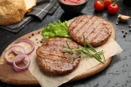 Delicious hamburger patties, tomatoes and spices on black table, closeupの写真素材
