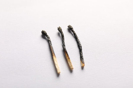 Burnt matches on light grey background, closeup view