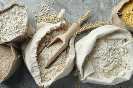 Different types of flour in bags on grey textured table, flat layの写真素材