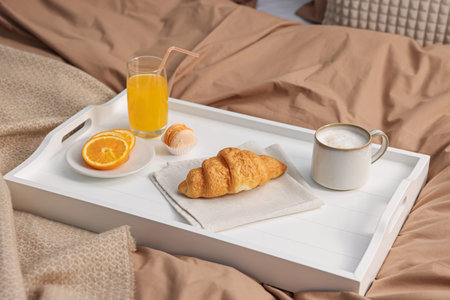 Tray with delicious breakfast on bed indoors, closeup