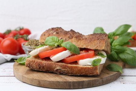 Tasty sandwich with mozzarella cheese, tomatoes and basil on white wooden table, closeupの写真素材