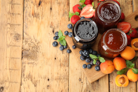 Different jams in jars and ingredients on wooden table, flat lay. Space for textの写真素材