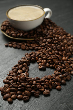 Aromatic coffee in cup and heart shaped of beans on black table, closeupの写真素材