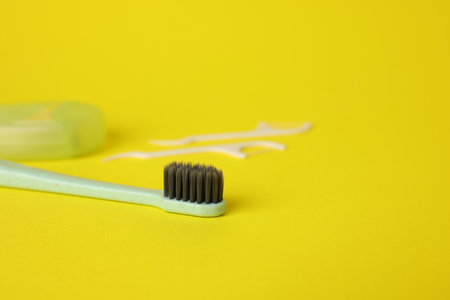Toothbrush and floss picks on yellow background, closeup. Space for textの写真素材