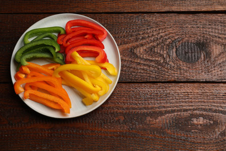 Cut colorful bell peppers on wooden table, top view. Space for textの写真素材