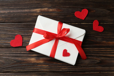 Stack of love letters and red hearts on wooden table, flat lay