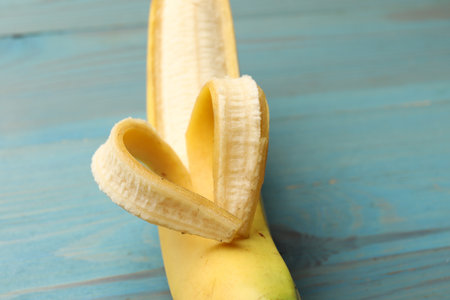 Banana with heart made of peel on light blue wooden table, closeupの写真素材