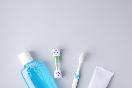 Different oral care products on light grey background, flat lay. Space for text