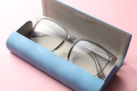 Case with stylish glasses on pink background, closeup