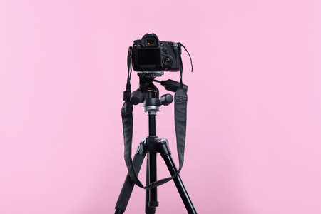 Modern professional video camera on pink background