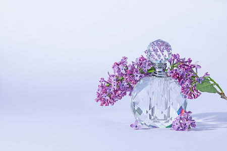 Perfume bottle and branch with lilac flowers on light grey background, closeup. Space for textの写真素材