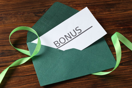 Card with word Bonus, envelope and ribbon on wooden table, above viewの写真素材