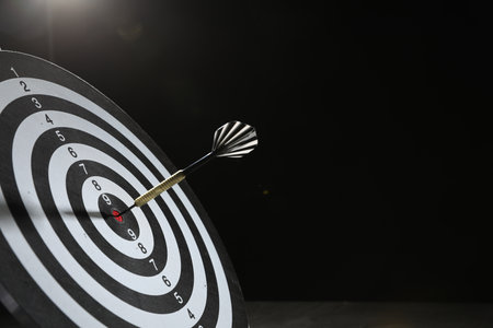 Targeting. Dart board with arrow on dark background, space for textの写真素材