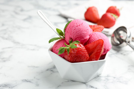 Refreshing sorbet, strawberries and mint in bowl on white marble table, closeup. Space for textの写真素材