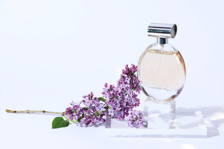 Perfume bottle and branch with lilac flowers on light grey background, closeupの写真素材
