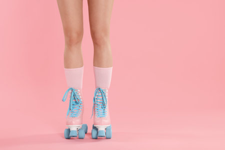 Woman in roller skates on pink background, closeup. Space for textの写真素材