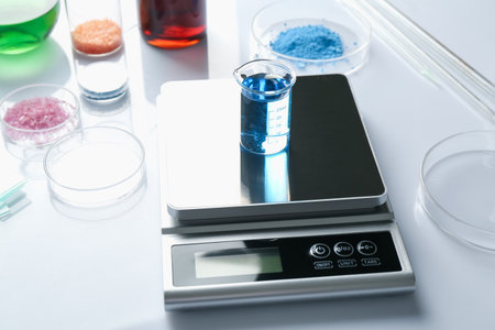 Scale with beaker of sample and other laboratory equipment on white background, closeupの写真素材