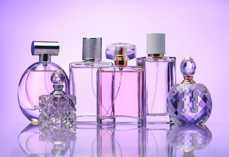 Bottles of perfume on mirror surface against pale violet gradient backgroundの写真素材