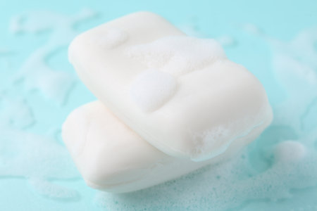 Soap bars with foam on light blue background, closeupの写真素材
