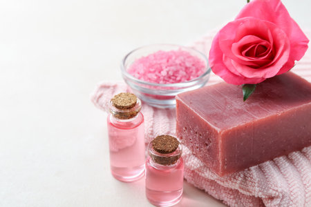 Aromatic soap bar, rose, towel and cosmetic products on light tableの写真素材