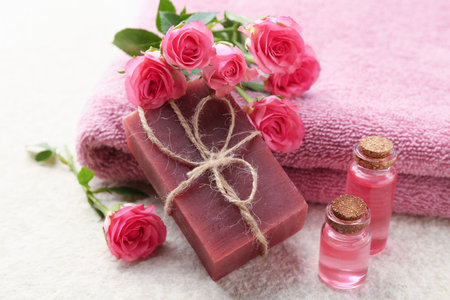 Soap bar, towels, essential oils and beautiful roses on beige table, closeupの写真素材