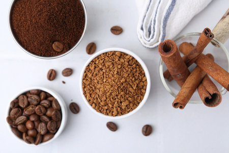 Different types of instant coffee, beans and cinnamon sticks on light table, flat layの写真素材