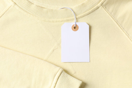 Cardboard tag on beige garment, top view