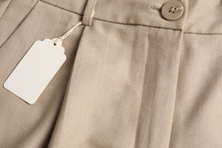Cardboard tag on beige pants, above view