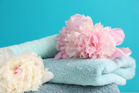 Soft towels and peony flowers on light blue background, closeupの写真素材