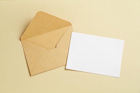 Blank invitation card and envelope on beige background, flat lay. Space for designの写真素材