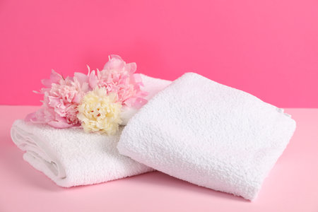 Soft towels and peony flowers on pink backgroundの写真素材
