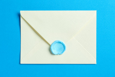 Beautiful invitation envelope with wax seal on light blue background, top viewの写真素材