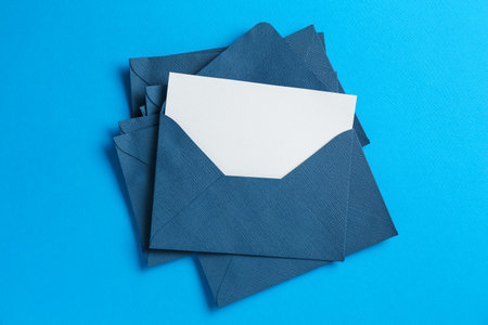 Blank invitation card and envelopes on light blue background, top viewの写真素材