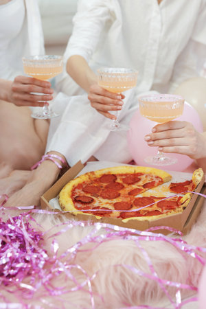 Pajama day. Friends with glasses of alcoholic drink and pizza on faux fur, closeupの写真素材