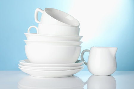 Different clean dishes on white table against light blue backgroundの写真素材