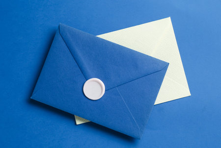 Beautiful invitation envelope and card on blue background, top view