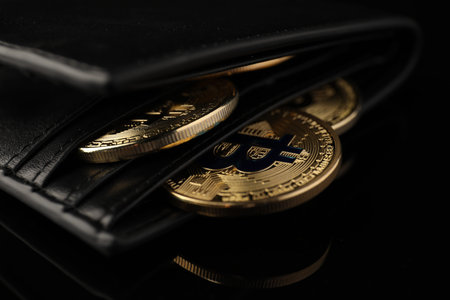 Cryptocurrency. Bitcoins in wallet on black mirror surface, closeup