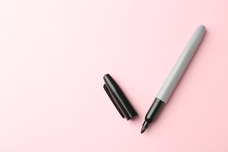 One black marker on light pink background, top view. Space for textの写真素材