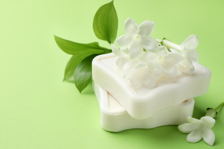 Bars of soap and jasmine flowers on light green background, closeup. Space for textの写真素材