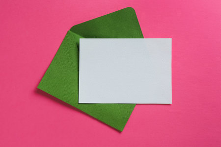 Blank invitation card and envelope on pink background, top view. Space for designの写真素材