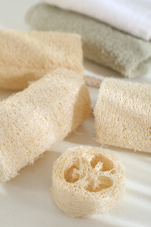 Different loofah sponges and towels on white table, closeupの写真素材