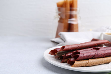 Tasty fruit leather rolls on white table, closeup. Space for textの写真素材