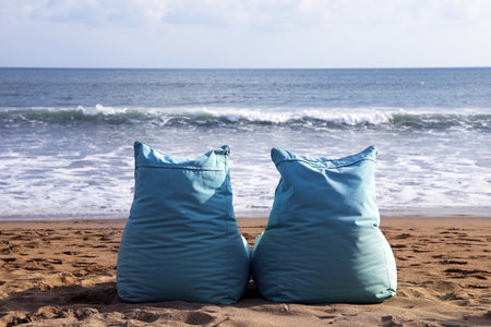 Light blue bean bag chairs on sandy beach by seaの写真素材